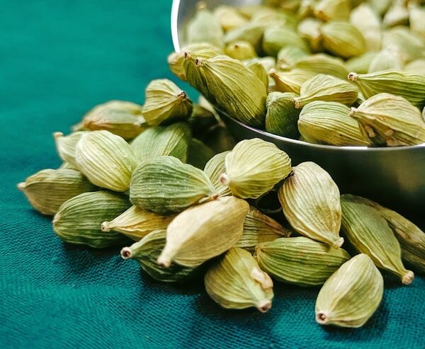 Green cardamom pods in a metal bowl